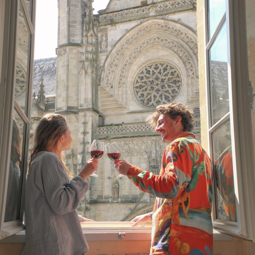 Deux personnes trinquant avec des verres de vin donnant une la magnifique Basilique Saint-Michel de Bordeaux.