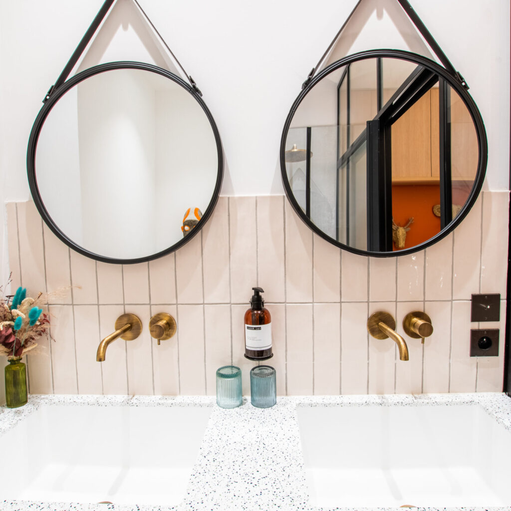 Salle de bain de la chambre supérieure du LOLA Boutique Hôtel avec miroirs doubles et double vasques élégantes.