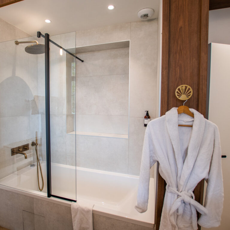 Salle de bain moderne avec douche et peignoirs suspendus dans la chambre duplex balcon - Vue Basilique du LOLA Boutique Hôtel.