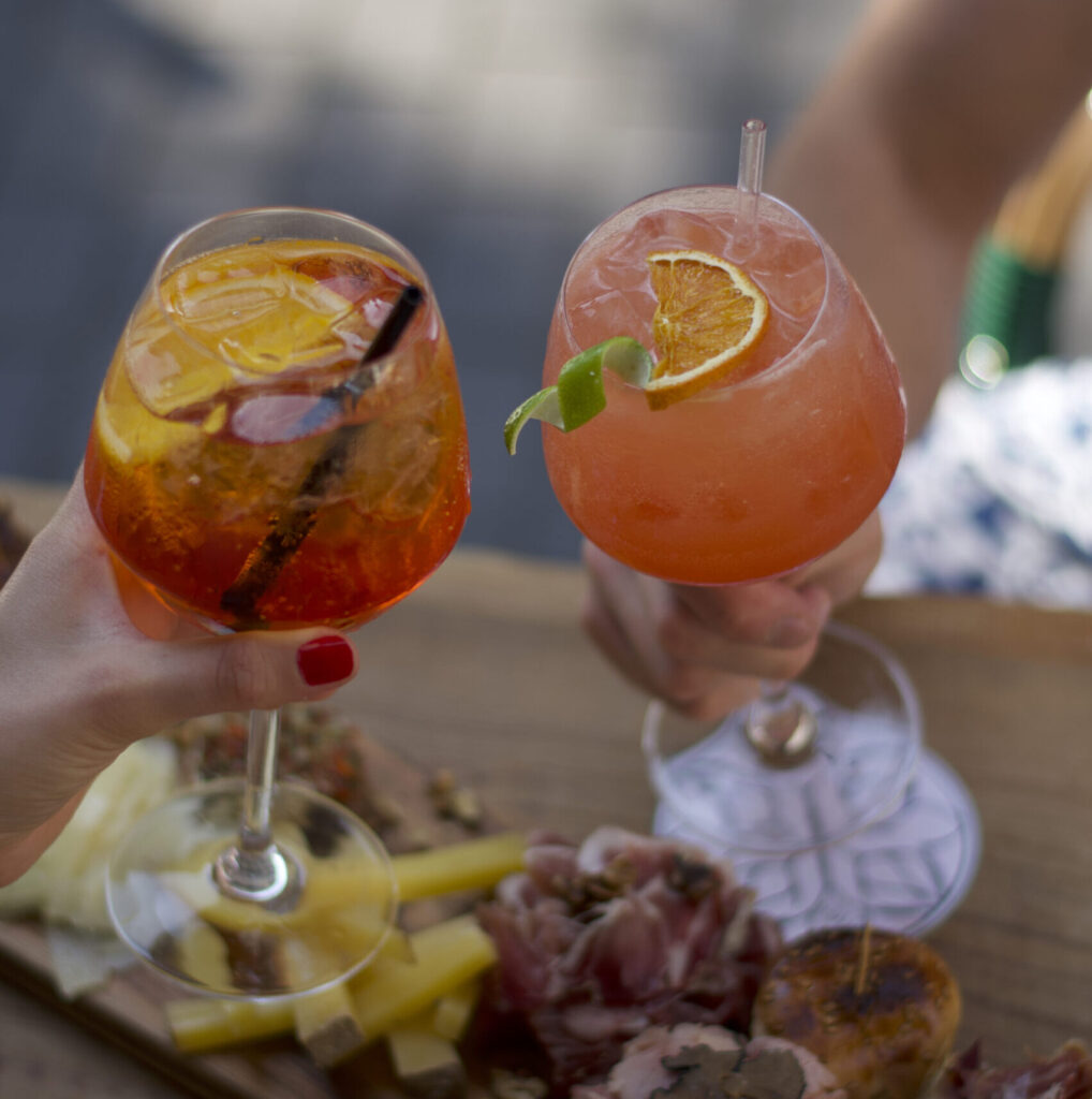 Deux cocktails colorés servis sur une table en extérieur, illustrant l’offre rafraîchissante du LOLA’s Bar.