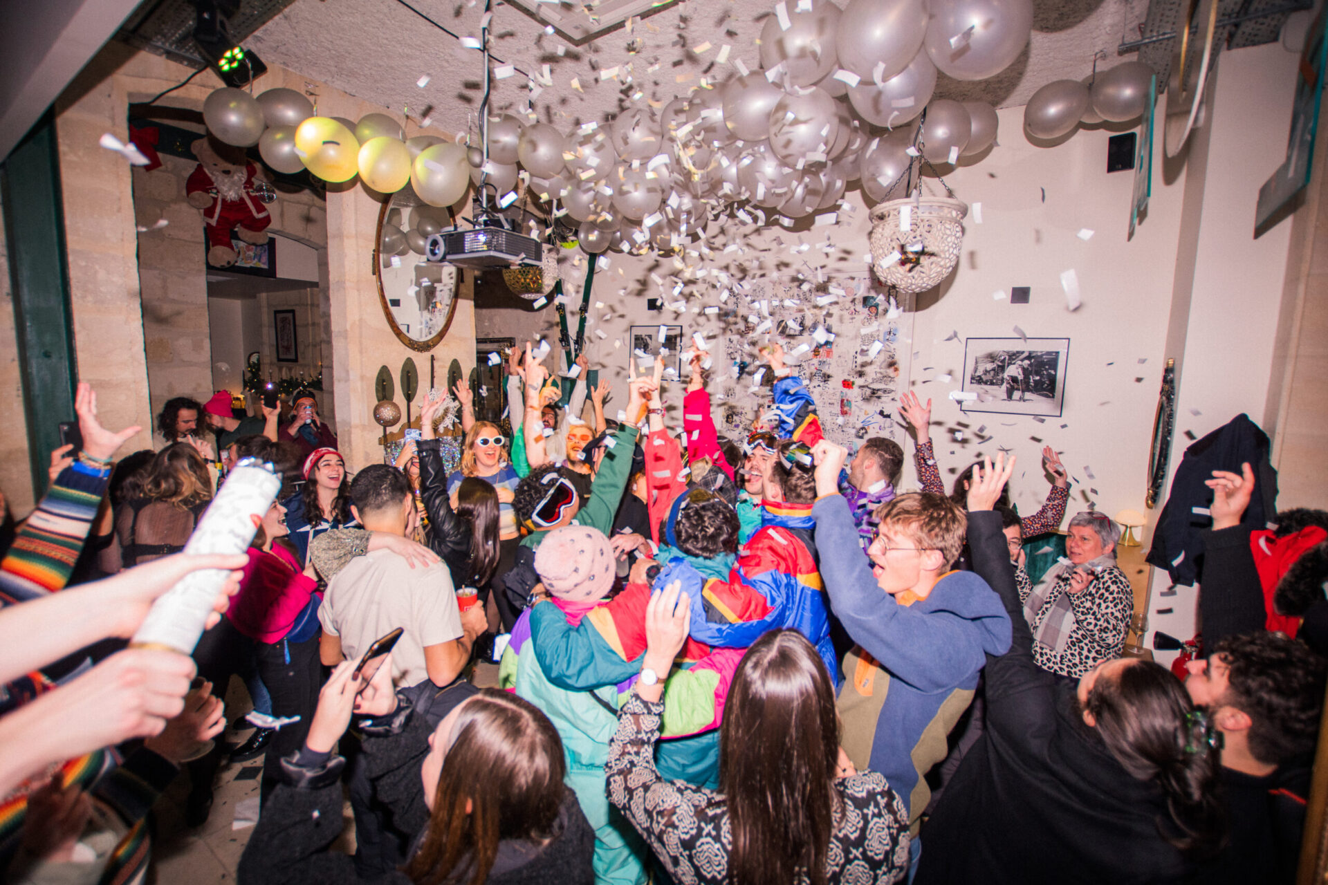 Ambiance festive et animée lors d’une soirée au LOLA’s Bar à Bordeaux, avec des invités en tenue colorée célébrant sous une pluie de confettis